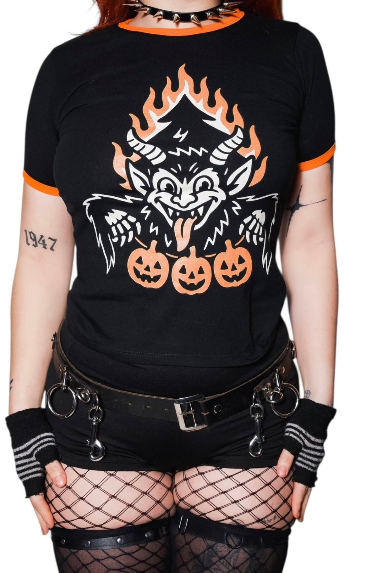 Person wearing a black t-shirt with a graphic design of a wolf and pumpkins, paired with fishnet stockings and black gloves.