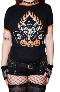 Person wearing a black t-shirt with a graphic design of a wolf and pumpkins, paired with fishnet stockings and black gloves.