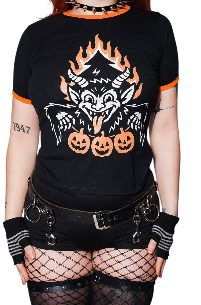 Person wearing a black t-shirt with a graphic design of a wolf and pumpkins, paired with fishnet stockings and black gloves.