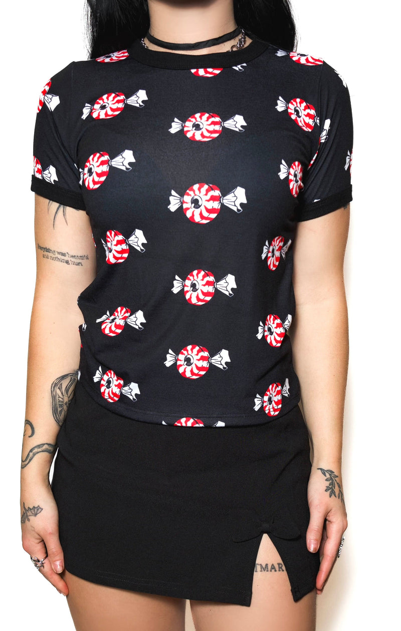 Person wearing a black t-shirt with candy cane pattern and black skirt on a white background