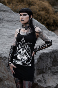 Person with tattoos and dark makeup standing on rocky terrain