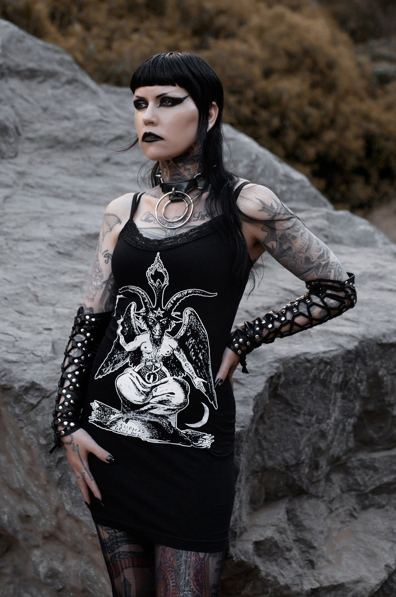 Person with tattoos and dark makeup standing on rocky terrain