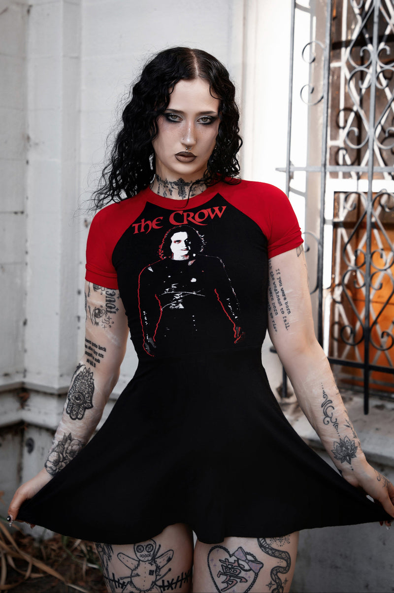 Person wearing a black and red 'The Crow' t-shirt with tattoos.