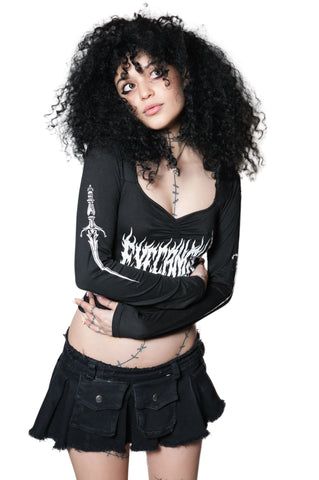 Person wearing a black long-sleeve top with white graphics and a black skirt on a white background