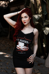 Woman with red hair wearing a black tank top with graphic design outdoors.