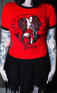 Person wearing a red t-shirt with a graphic design and 'Dracula' text, standing against a dark background.