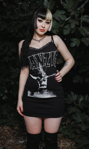 Person wearing a black tank top with graphic design and text, standing against a dark background.