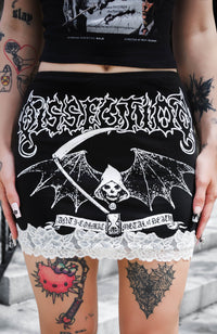 Person wearing a black skirt with white graphic design and text, standing on steps.