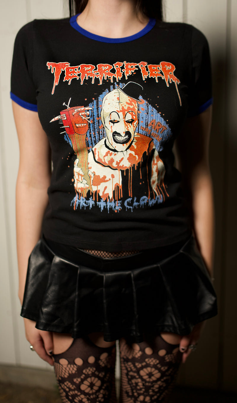 Person wearing a black t-shirt with a graphic design of a clown and text, paired with a black leather skirt.