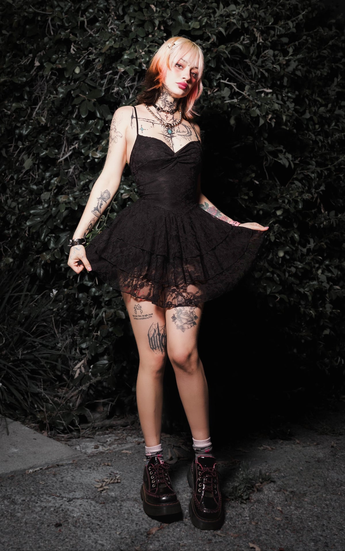 Person wearing a black dress with sheer overlay against a dark background