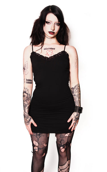 Person wearing a black dress and fishnet stockings on a white background
