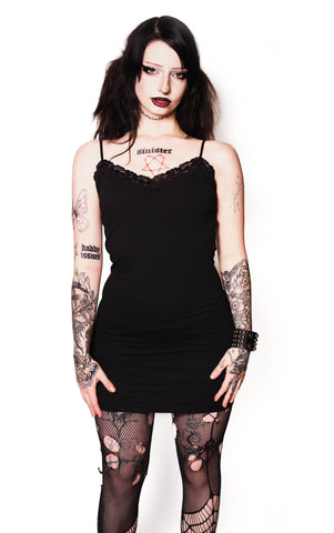 Person wearing a black dress and fishnet stockings on a white background