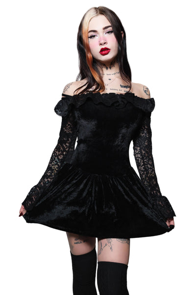 Woman wearing a black off-shoulder dress with lace sleeves on a white background