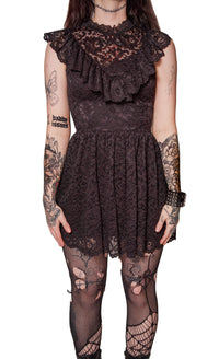 Person wearing a black lace dress with ruffled top on a white background