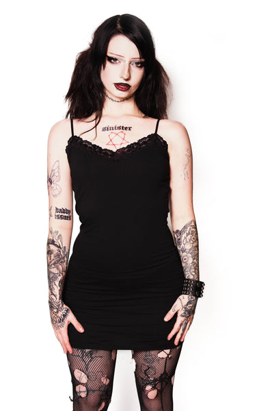 Person wearing a black dress and fishnet stockings on a white background