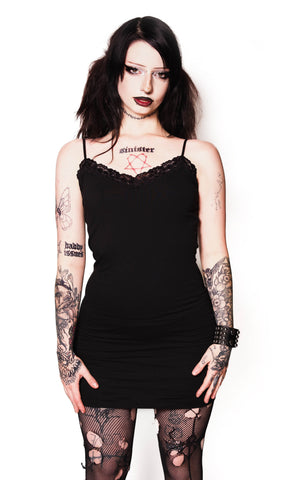 Person wearing a black dress and fishnet stockings on a white background