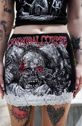 Person wearing a black and red 'Cannibal Corpse' skirt with a skull design.