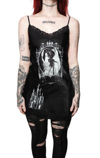 Person wearing a black tank top with a graphic design and black pants on a white background