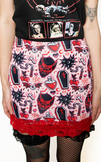 Skirt with gothic design featuring skulls, hearts, and crosses on a white background.