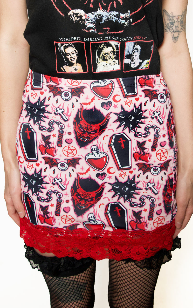 Skirt with gothic design featuring skulls, hearts, and crosses on a white background.