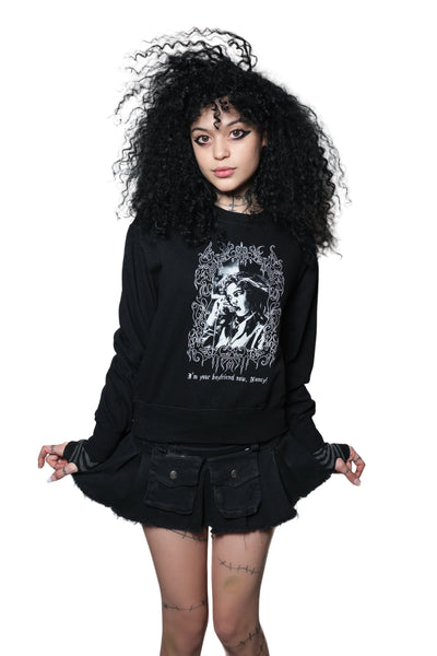 Person wearing a black oversized sweatshirt with graphic design on a white background