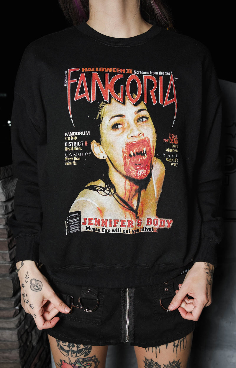 Person wearing a black sweatshirt with a graphic design and text, standing against a dark background.