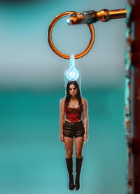 Keychain with a miniature figure of a woman in a red top and black shorts against a gradient background.