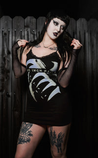 Person wearing a black dress with white designs against a dark background