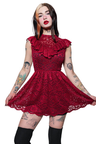 Woman wearing a red lace dress with ruffled details on a white background