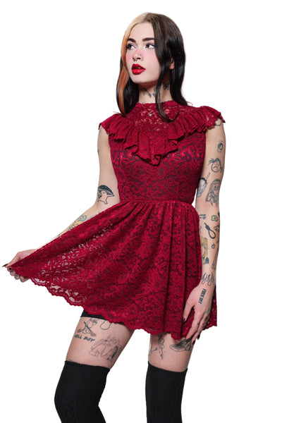 Woman wearing a red lace dress with ruffled details on a white background