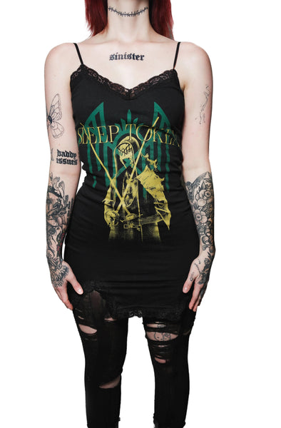 Person wearing a black tank top with a graphic design and text, standing against a white background.