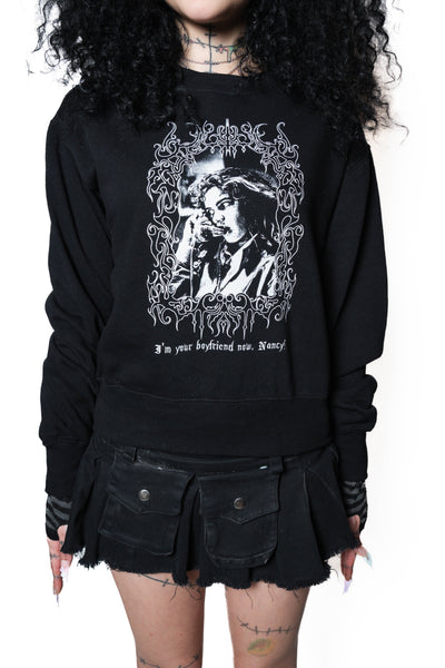 Person wearing a black sweatshirt with graphic design and text.