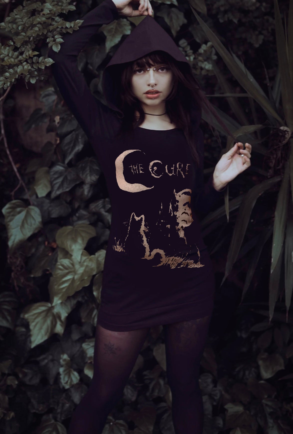 Person wearing a dark hoodie with a graphic design in a natural setting