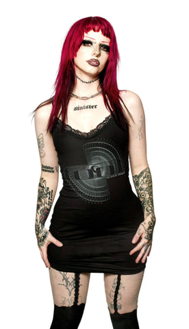 Woman with red hair and tattoos wearing a black dress with geometric design on a white background