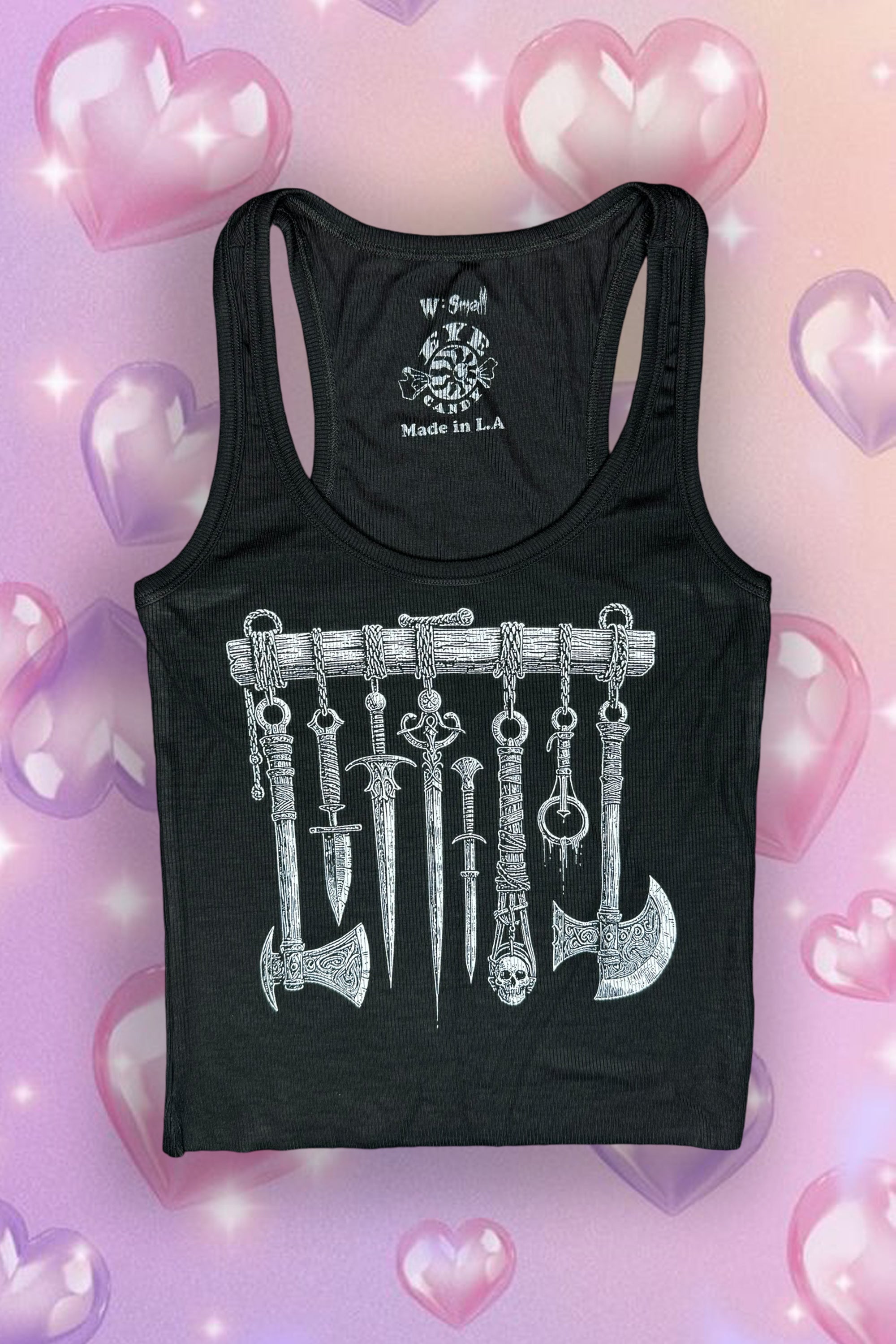 A black ribbed tank top with a graphic print of medieval weapons on the front, displayed on a mannequin against a pink heart-themed background.