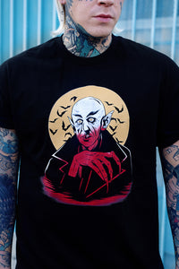 Black short sleeve T-shirt. Features white and orange image of vampire. Yellow full moon and black bats in background of image.