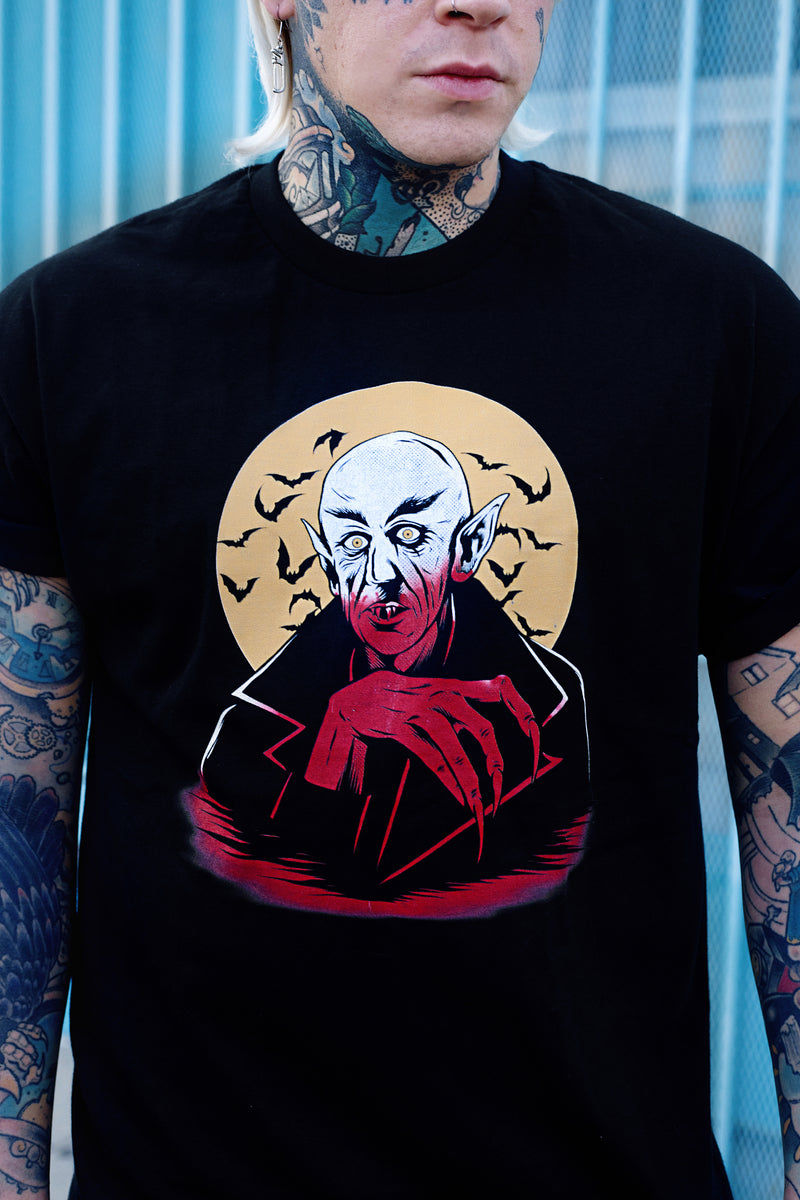Black short sleeve T-shirt. Features white and orange image of vampire. Yellow full moon and black bats in background of image.