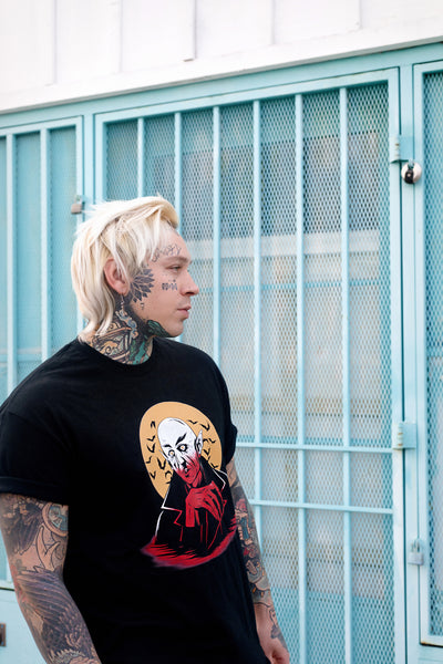 Black short sleeve T-shirt. Features white and orange image of vampire. Yellow full moon and black bats in background of image.