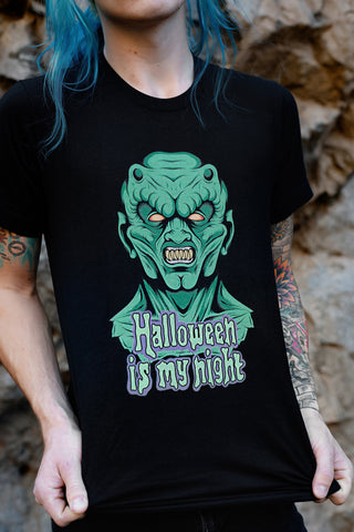 Black short sleeve t-shirt. Features green monster with yellow eyes. Inscription reads "Halloween is my night" in green.