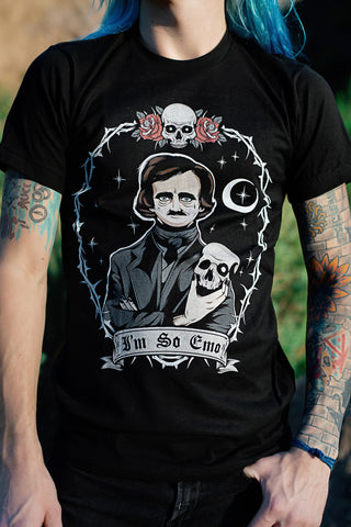 Black short sleeve t-shirt. Print features Edgar Allen Poe holding a skull with moon and sparkles in background inside circle shape bob wire. Skull and roses located on top part of circle bob wire. Inscription reads "I'm so emo" in black font.