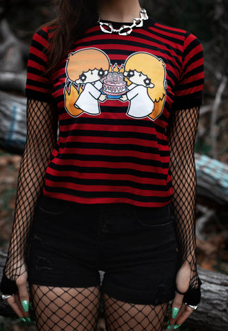 Black and red stripped ringer tee with black trim. Features image of cartoon boy and girl wearing white dresses with black makeup on eyes and black upside down cross on foreheads. They are holding a white cake with pink frosting and pink 666 candles lit on cake. 