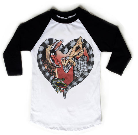 White baseball tee with black sleeves and black neckline trim. Features image of Barbara and Adam from the movie Beetlejuice. Barbara has face stretched with mouth open, tongue sticking out and eyes in mouth. Adam has his face stretched out with eyeballs on his fingers and glasses in hand. Black and white Beetlejuice snake around Adam and Barbara in the shape of a heart.