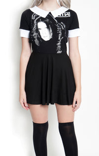 Black baby doll short sleeve dress with white collar and white cuffs. White print features man with black gloves holding his face. Inscription reads "NIN" in white.