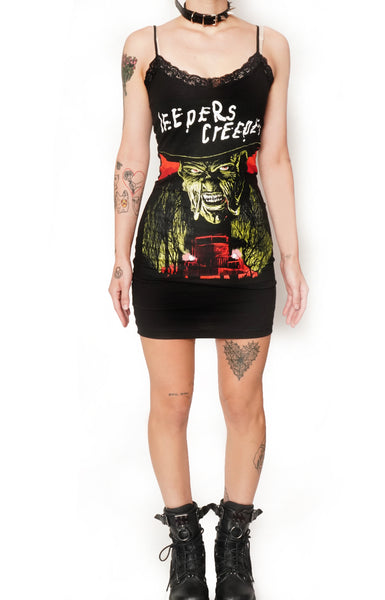 Black thin strap mini dress with black lace trim neckline. Features image of creeper from the movie Jeepers Creepers. Inscription reads "JEEPERS CREEPERS" in white.