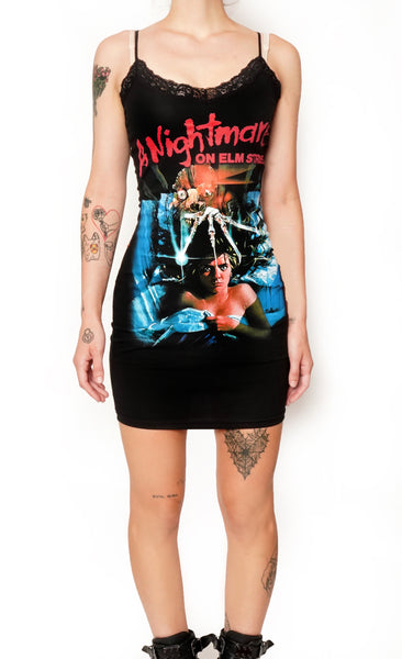 Black thin strap mini dress with black lace neckline. Features image on woman laying in bed under sheets with Freddy Krueger knife hand above her head. Inscription reads "A Nightmare ON ELM STREET" in red.