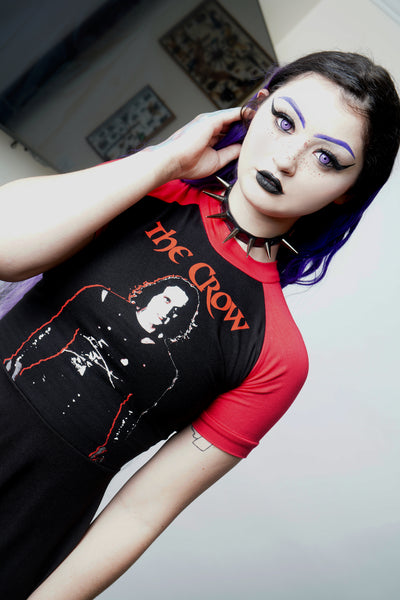 Black baby doll dress with red short sleeves and red trim neckline. Features image of Eric from the movie the Crow in black and white with red in background. Inscription reads "The Crow" in red.