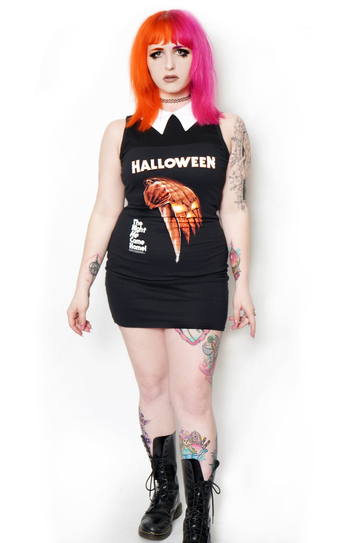 Black sleeveless mini dress with white polo collar. Print features pumpkin with knife and reads "Halloween" and "The Night He Comes Home" in white font