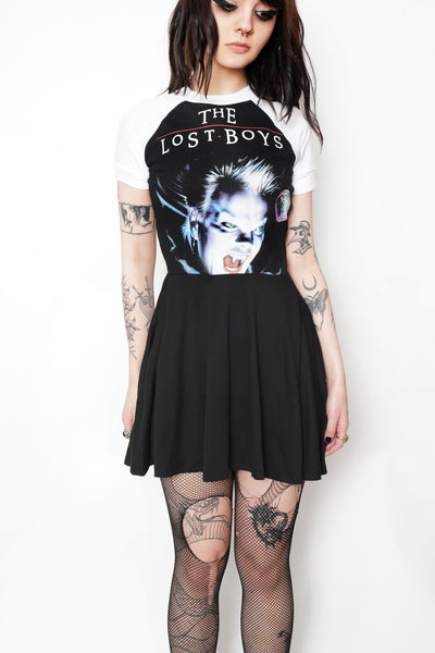 Black baby doll dress with white short sleeves and white trim neckline. Features picture of man with mouth open and fanged teeth. Inscription in white reads "THE LOST BOYS" in white.