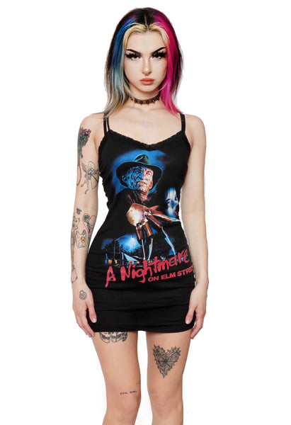 black mini dress with thin straps and lace trim neckline. Features Freddy Krueger with scared female. Beneath Freddy there are houses and a street light. Inscription reads "A Nightmare on Elm Street" in red.