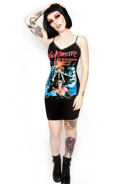 Black thin strap mini dress with black lace neckline. Features image on woman laying in bed under sheets with Freddy Krueger knife hand above her head. Inscription reads "A Nightmare ON ELM STREET" in red.